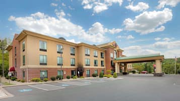 A multi-story hotel with a parking lot, a green awning, and a flag.