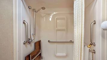 A shower area with grab bars, a wooden bench, and a towel rack.