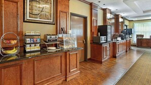 Zona de desayuno de hotel con un mostrador que exhibe cereales, un tostador y una máquina de café.