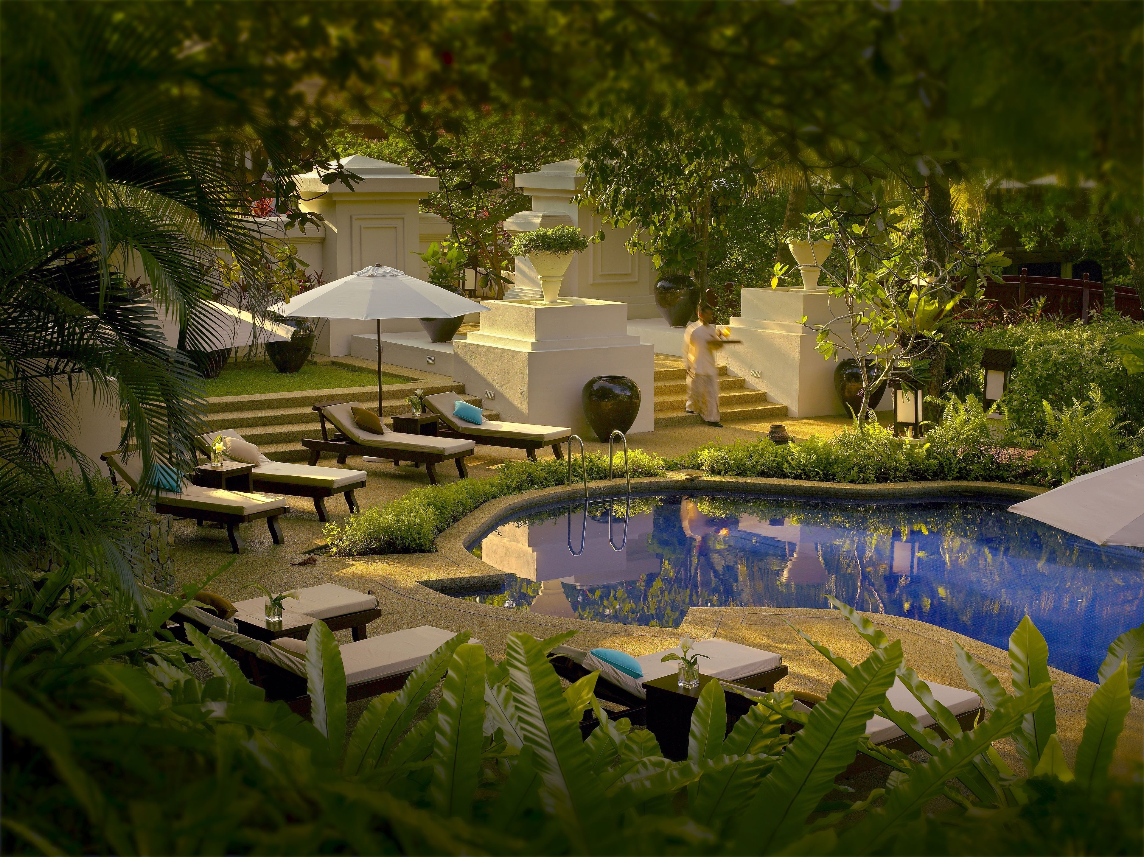 A poolside area with lounge chairs, a small pool, and steps leading to a covered area.