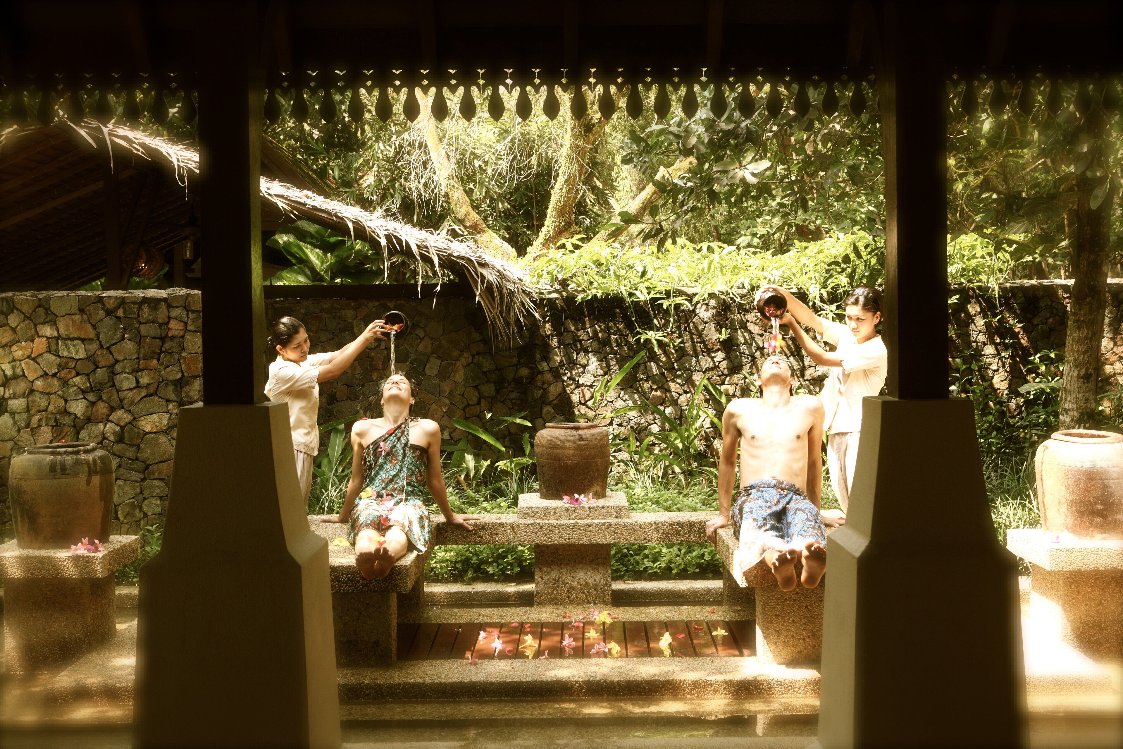 A stone structure with a water feature, surrounded by lush greenery.