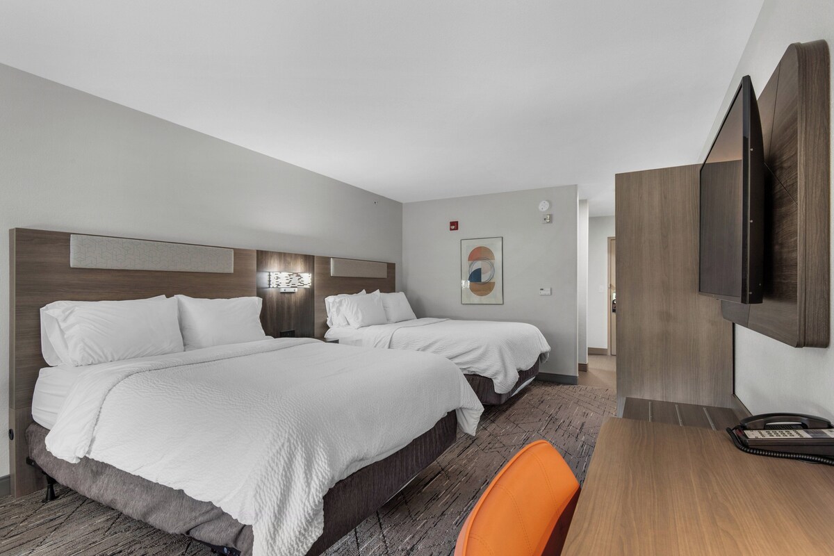 Een hotelkamer met twee bedden, een bureau en een televisie.