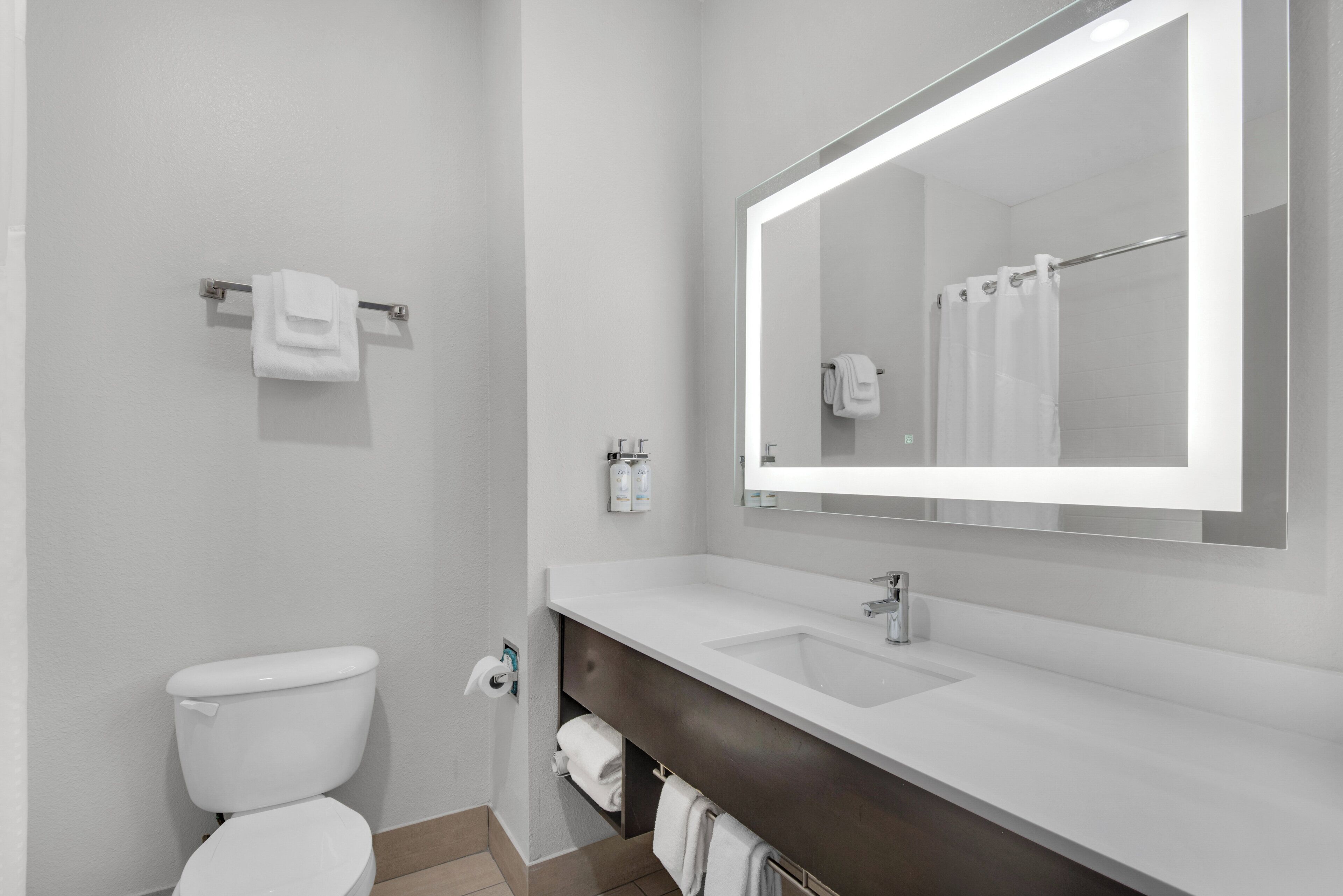 A modern bathroom with a toilet, sink, and mirror.
