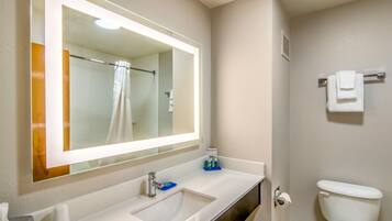 A bathroom with a large mirror, sink, and toilet.