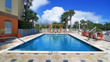 Una piscina al aire libre, sillones reclinables de piscina