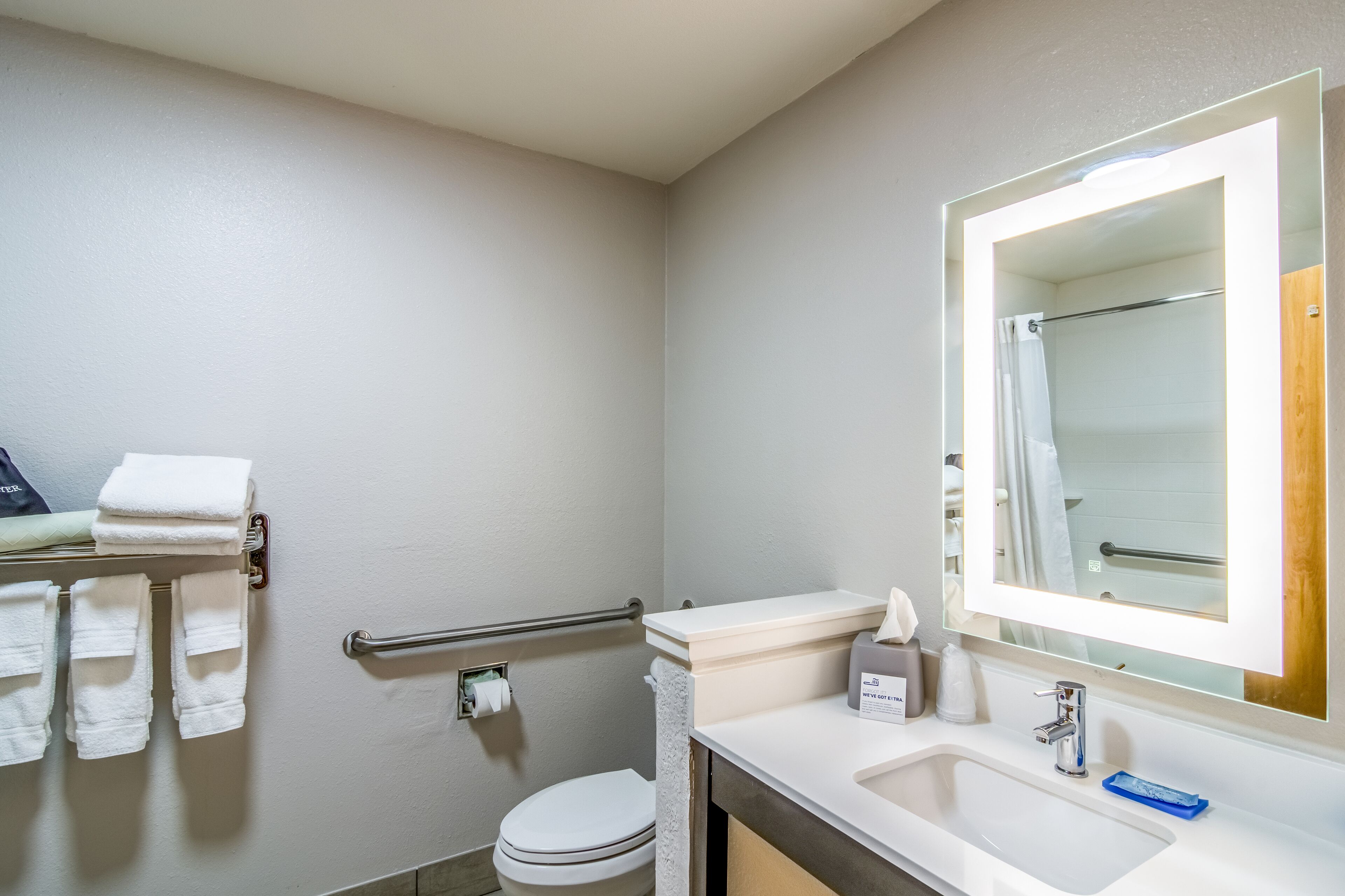 A modern bathroom with a toilet, sink, and a handrail.