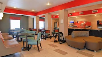 A hotel lobby with seating areas, a reception desk, and a counter with a coffee machine.