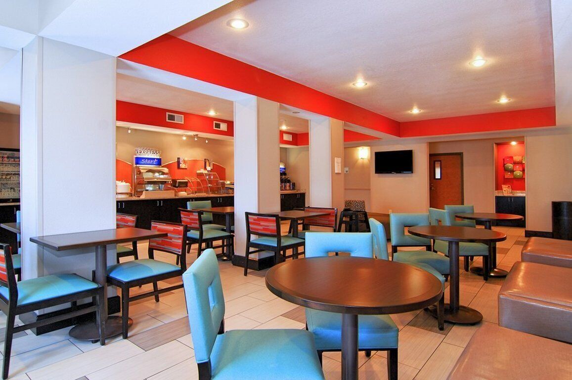 A modern restaurant with round tables and chairs, a coffee bar, and a flat-screen TV.