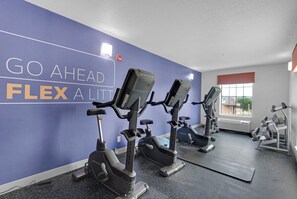 Een sportschool met hometrainers, een spiegel en een motiverende muur met de tekst 'GO AHEAD FLEX A LITTLE'.