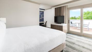 Habitació d'hotel amb un llit gran, una escriptoria amb televisió de pantalla plana, una cadira i una porta corredissa de vidre que dona a una zona exterior.