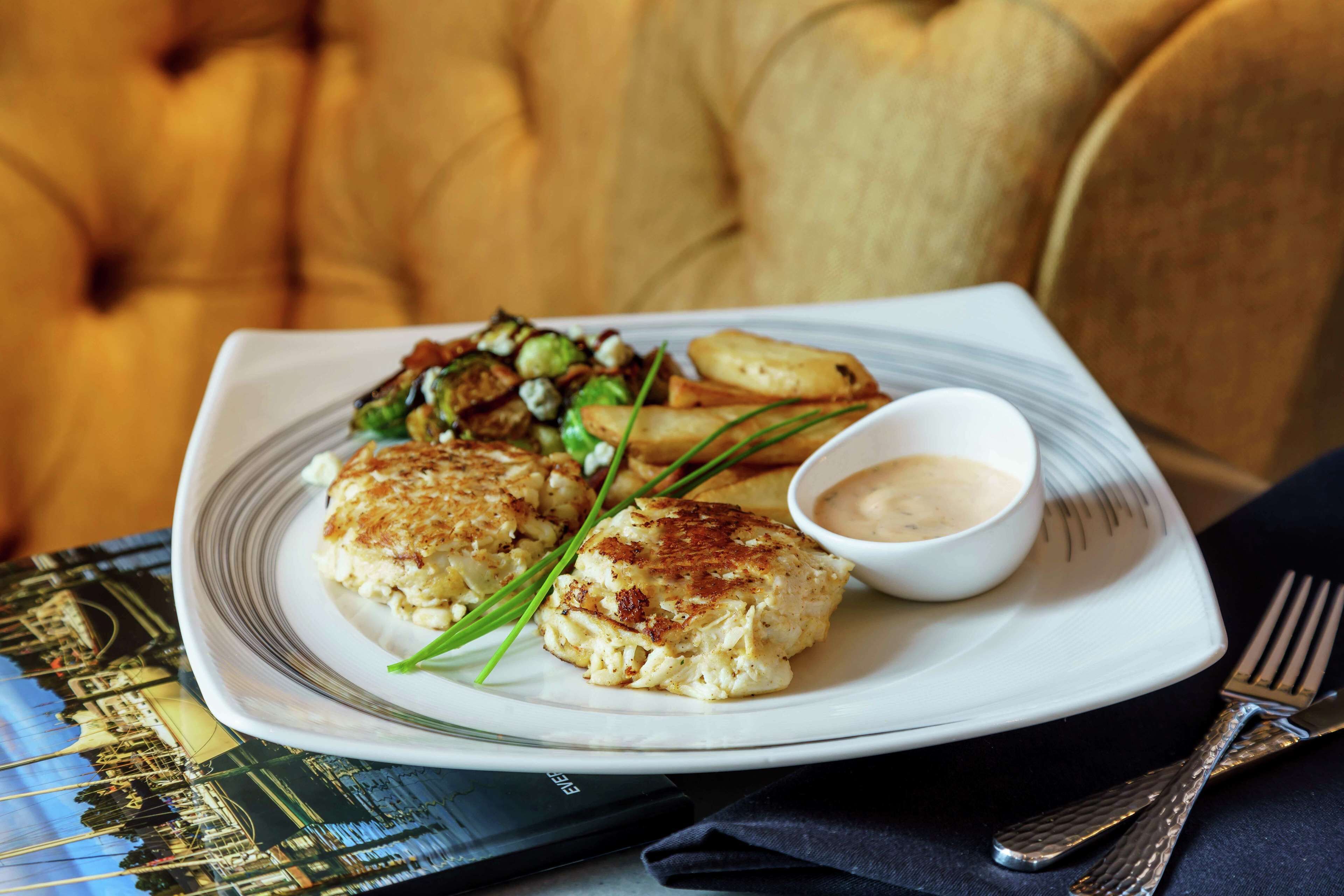 A plate of food with a side of sauce and a napkin with cutlery.