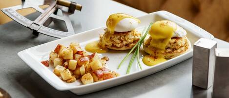 Un plato de desayuno con huevos benedictinos y patatas.