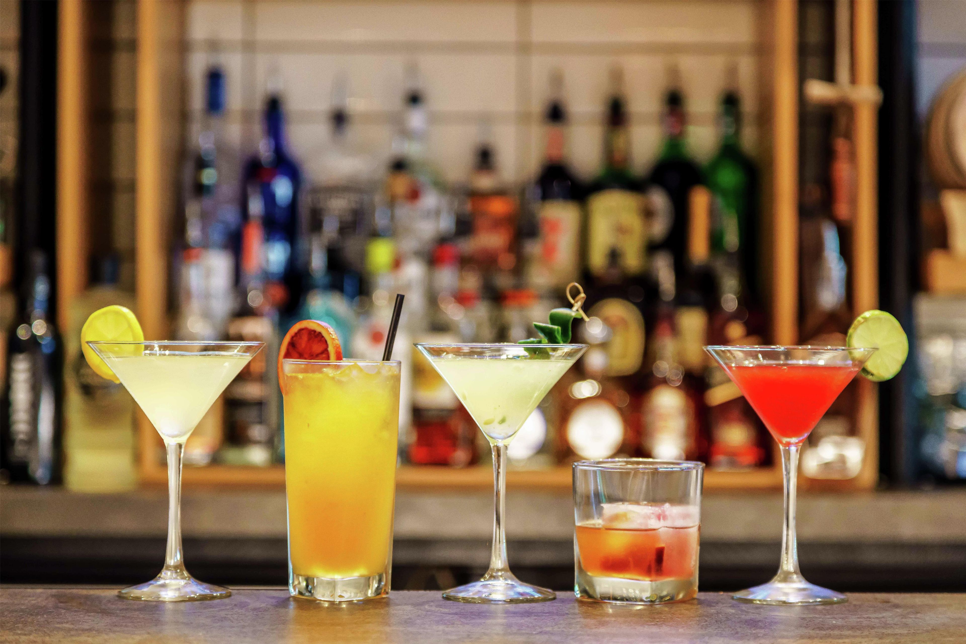 Un bar proposant divers cocktails et une sélection de bouteilles exposées en arrière-plan.