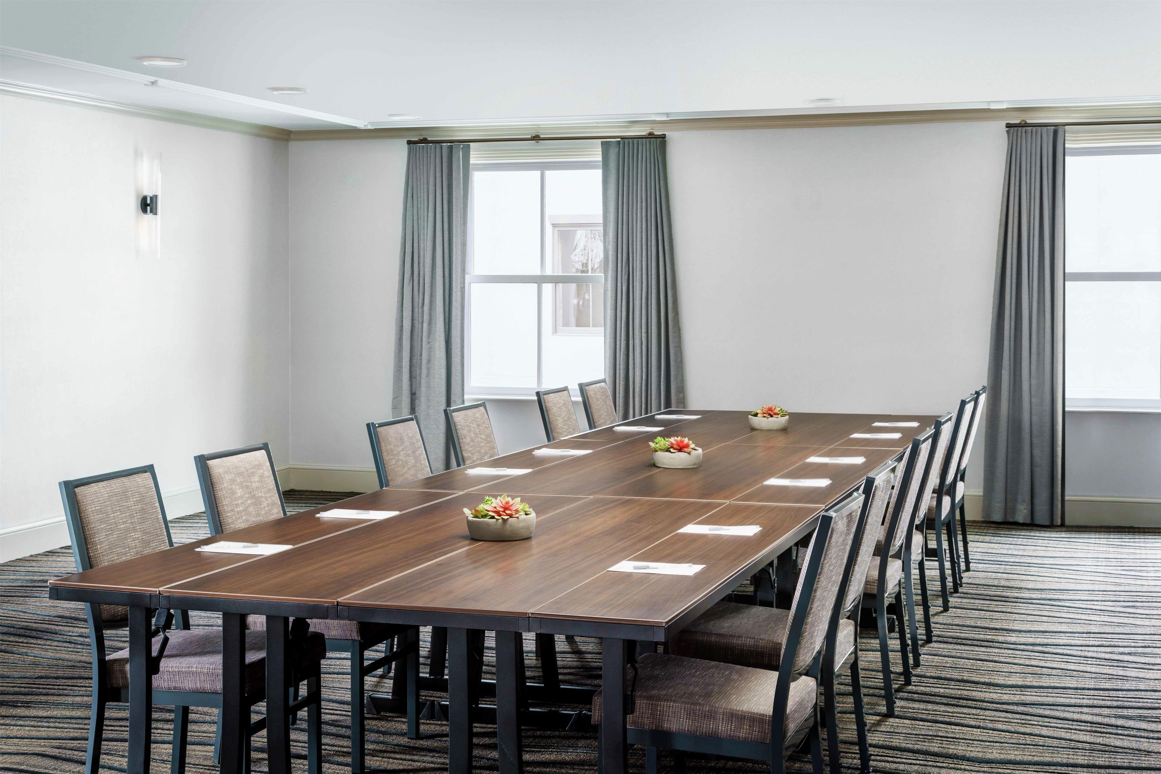 A conference room with a long table, chairs, and a carpeted floor.