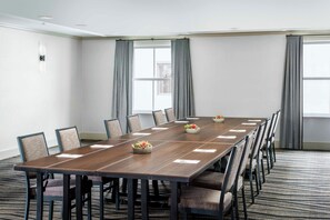 Un salón de conferencias con una mesa larga, sillas y suelo alfombrado.