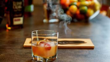 A glass of iced beverage with a slice of fruit on a wooden coaster.