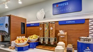 A breakfast buffet area with labeled sections for fruit and cereal, including bowls of apples and bananas, and dispensers for Quaker Oatmeal and other cereals. - Holiday Inn Express & Suites New Berlin by IHG (New Berlin)
