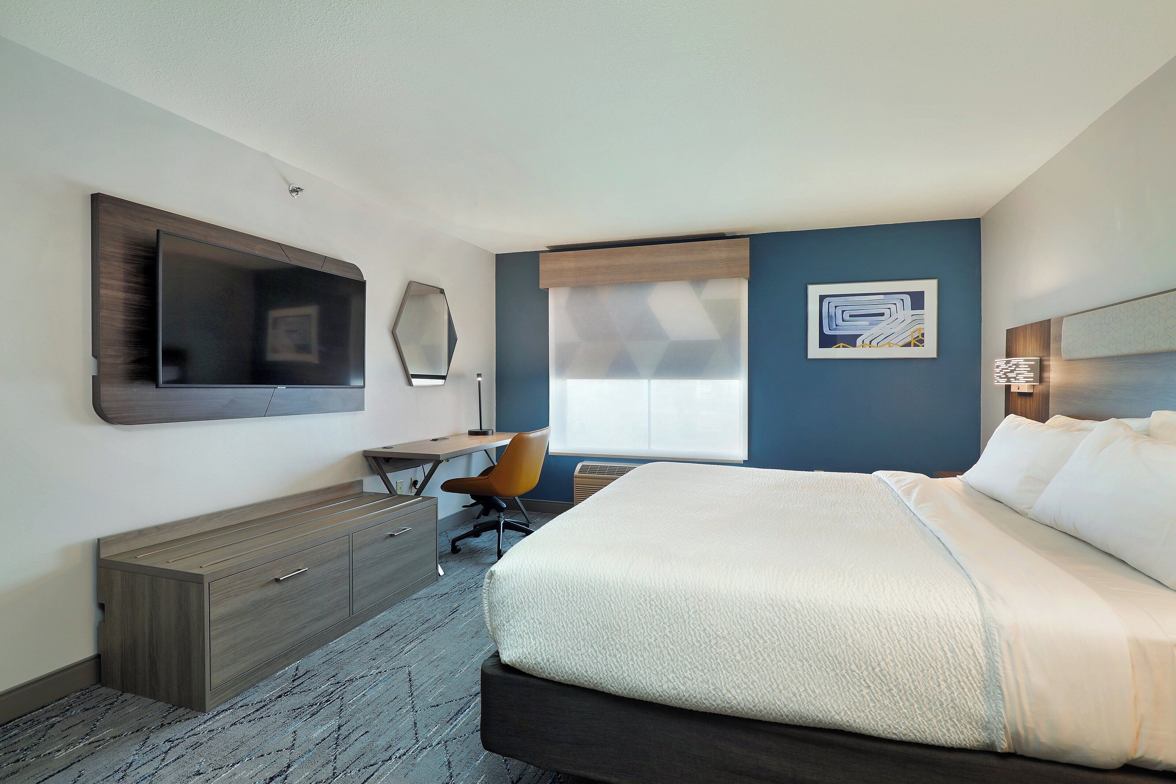 Une chambre d’hôtel moderne, dotée d’un grand lit, d’un bureau et d’une télévision.
