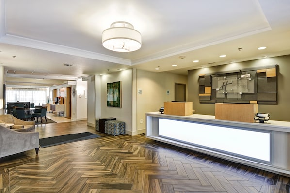 A hotel lobby with a reception desk, a dining area, and a hallway leading to other rooms.