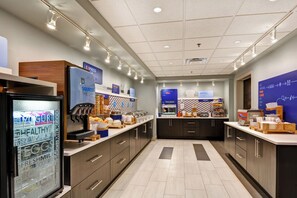 A modern breakfast area with a self-serve station, a refrigerated display case, and a bakery section. - Holiday Inn Express & Suites New Berlin by IHG (New Berlin)