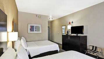A hotel room with two beds, a television, a desk, and a chair.