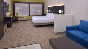 Ein Hotelzimmer mit Bett, Schreibtisch, Stuhl, Sofa und Fernseher.