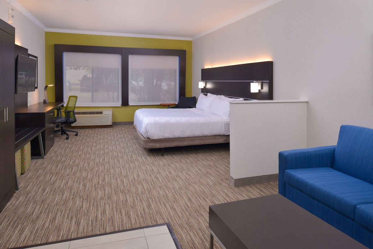 A hotel room with a bed, a desk, a chair, a sofa, and a TV.