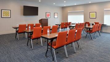 A conference room with tables and chairs, a podium, and a projection screen.