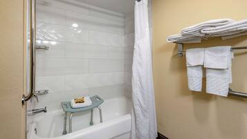 A bathroom with a white bathtub, a shower curtain, and a towel rack with folded towels.