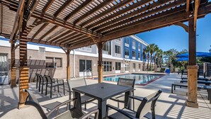 An outdoor patio area with a pool, wooden pergola, and seating arrangements. - BW Plus Flagler Beach Area Inn & Suites (Palm Coast)