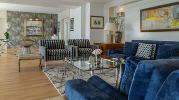 Una sala moderna con sofás a rayas, un sofá de terciopelo azul y una mesa de centro de vidrio.