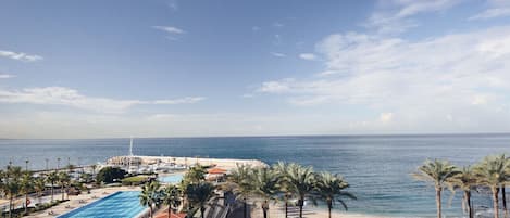 Un resort con piscina, playa y palmeras.