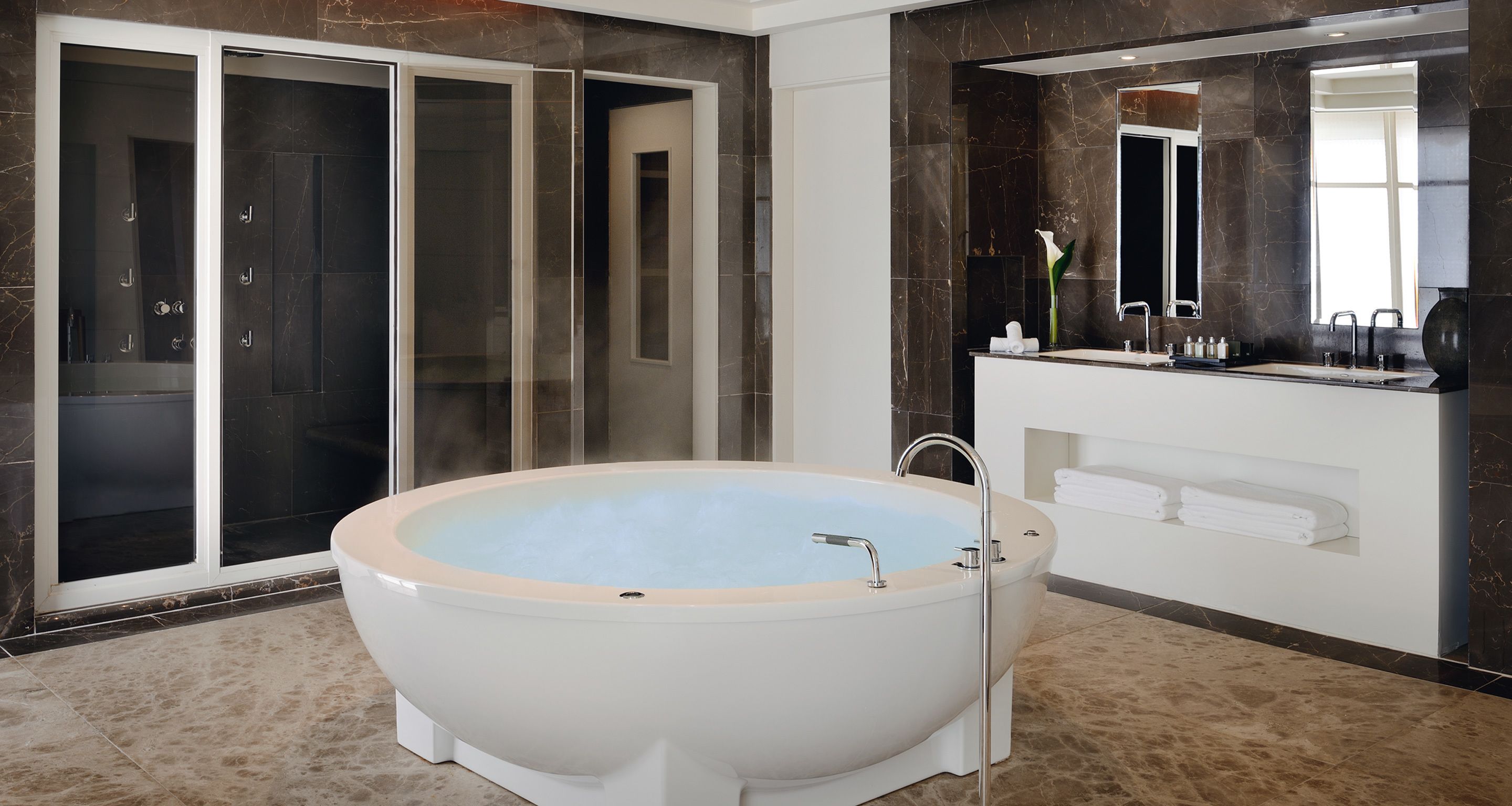 Un baño moderno con una bañera independiente, cabina de ducha con mampara de cristal y tocador con espejo.