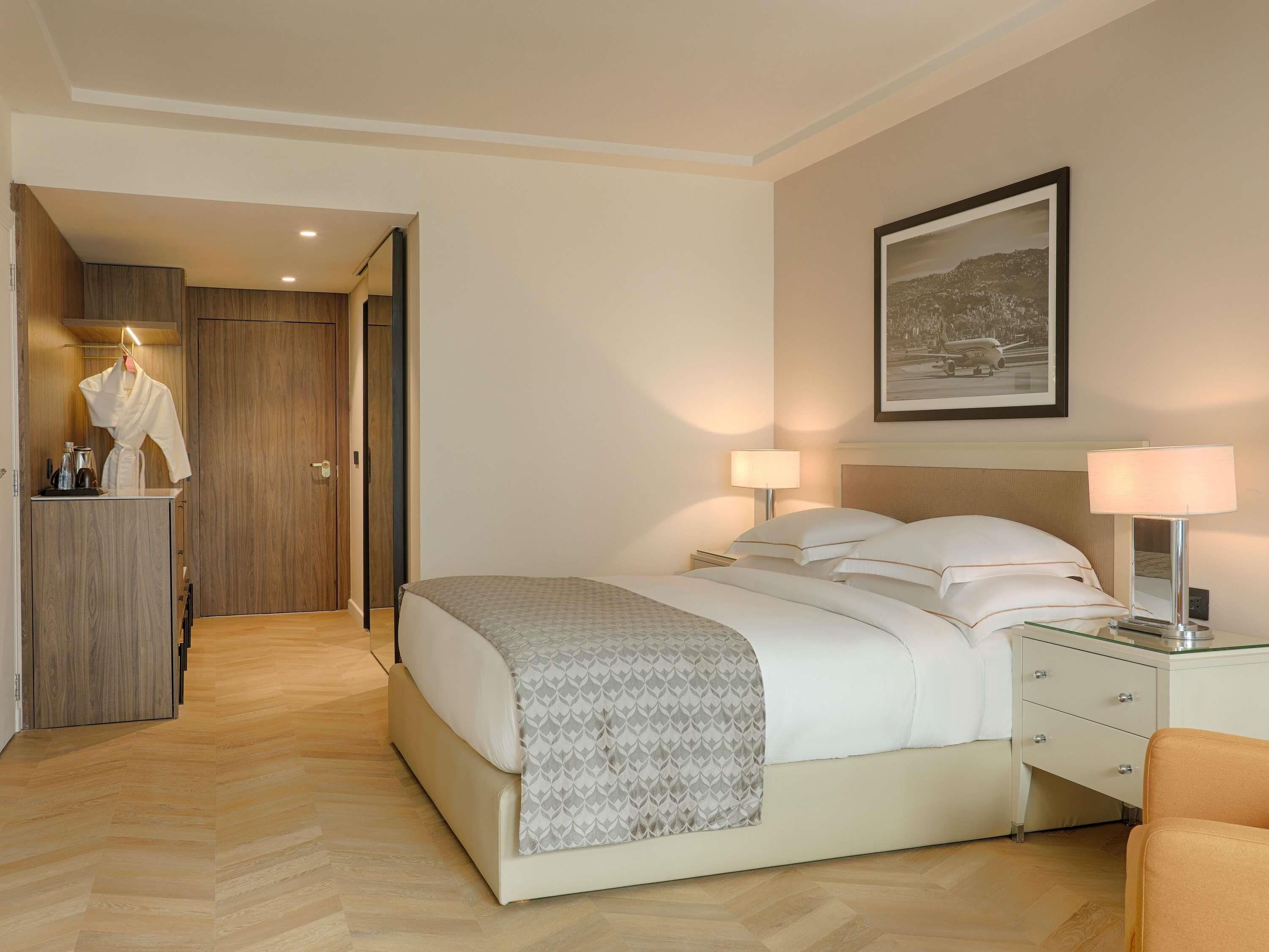 Una camera d'albergo con un letto, lampade da comodino, un tavolino notturno, un quadro appeso alla parete e un armadio in legno.