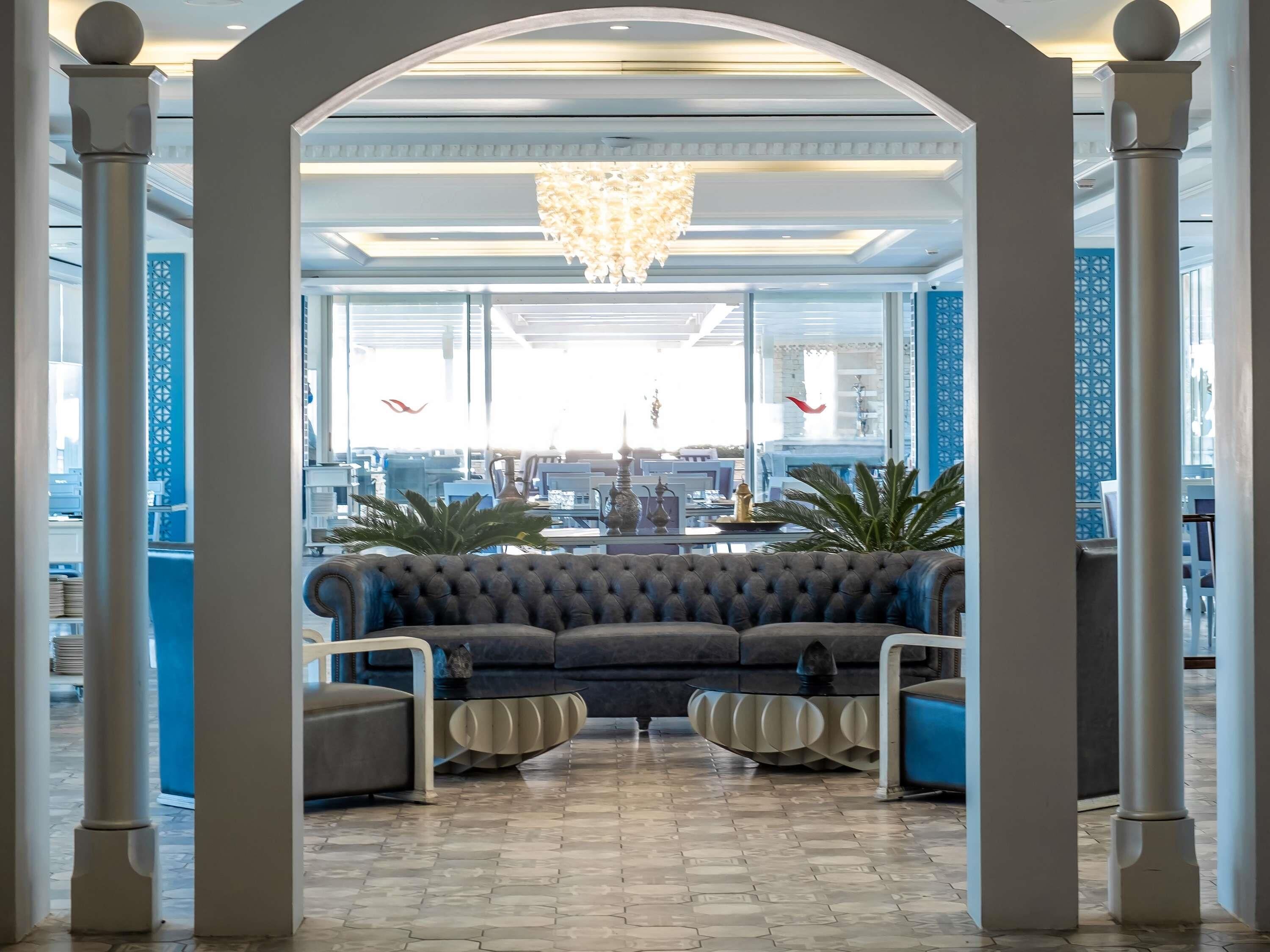 A lobby with a central seating area, a chandelier, and large windows.