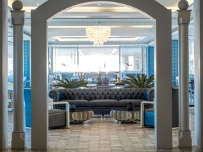 A lobby with a central seating area, a chandelier, and large windows. - Mövenpick Hotel Beirut (Beirut)
