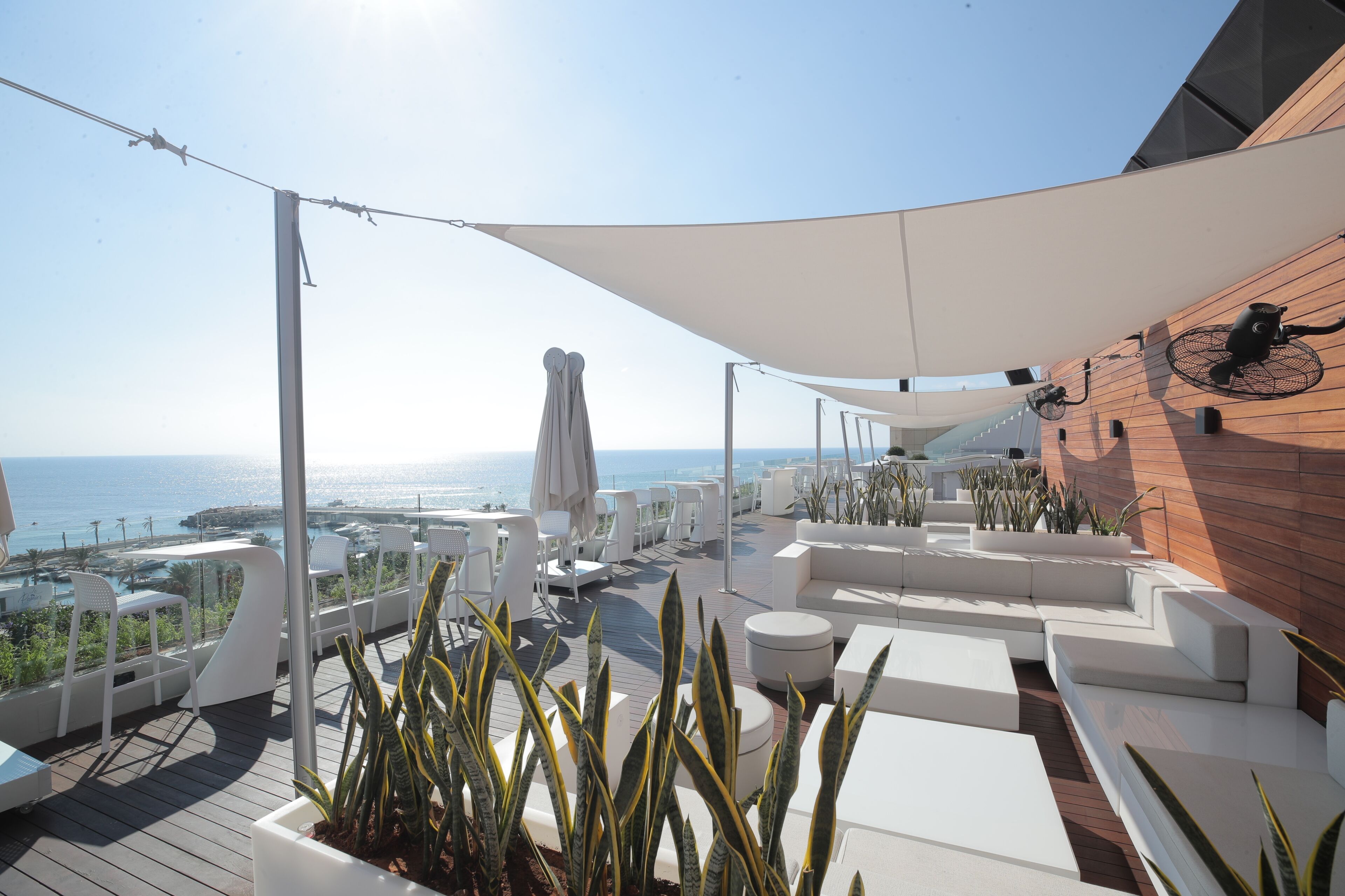 Un área de descanso al aire libre, moderna, con mobiliario blanco y vista al mar.