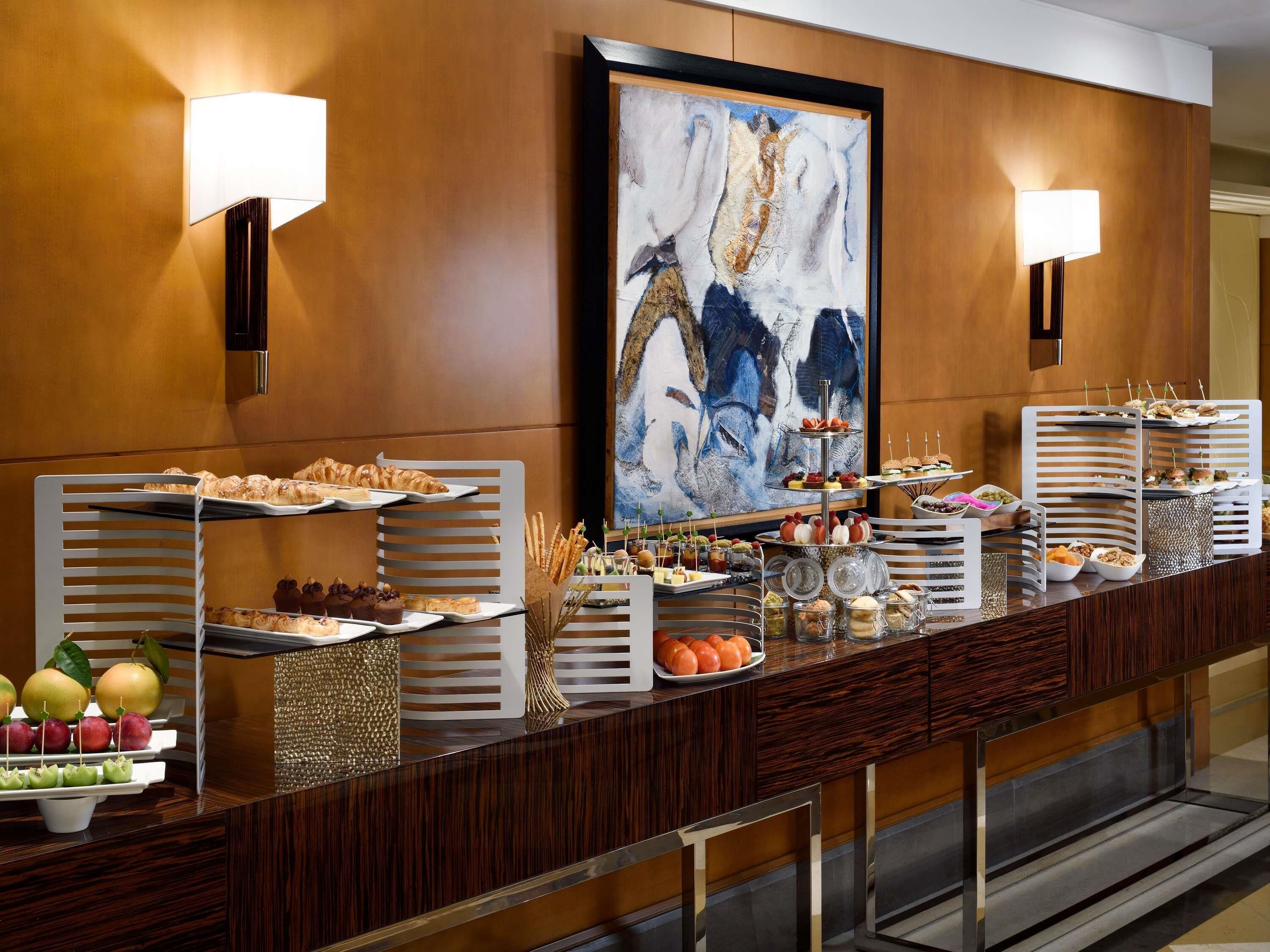 A buffet setup with various food items and a large abstract painting on the wall.