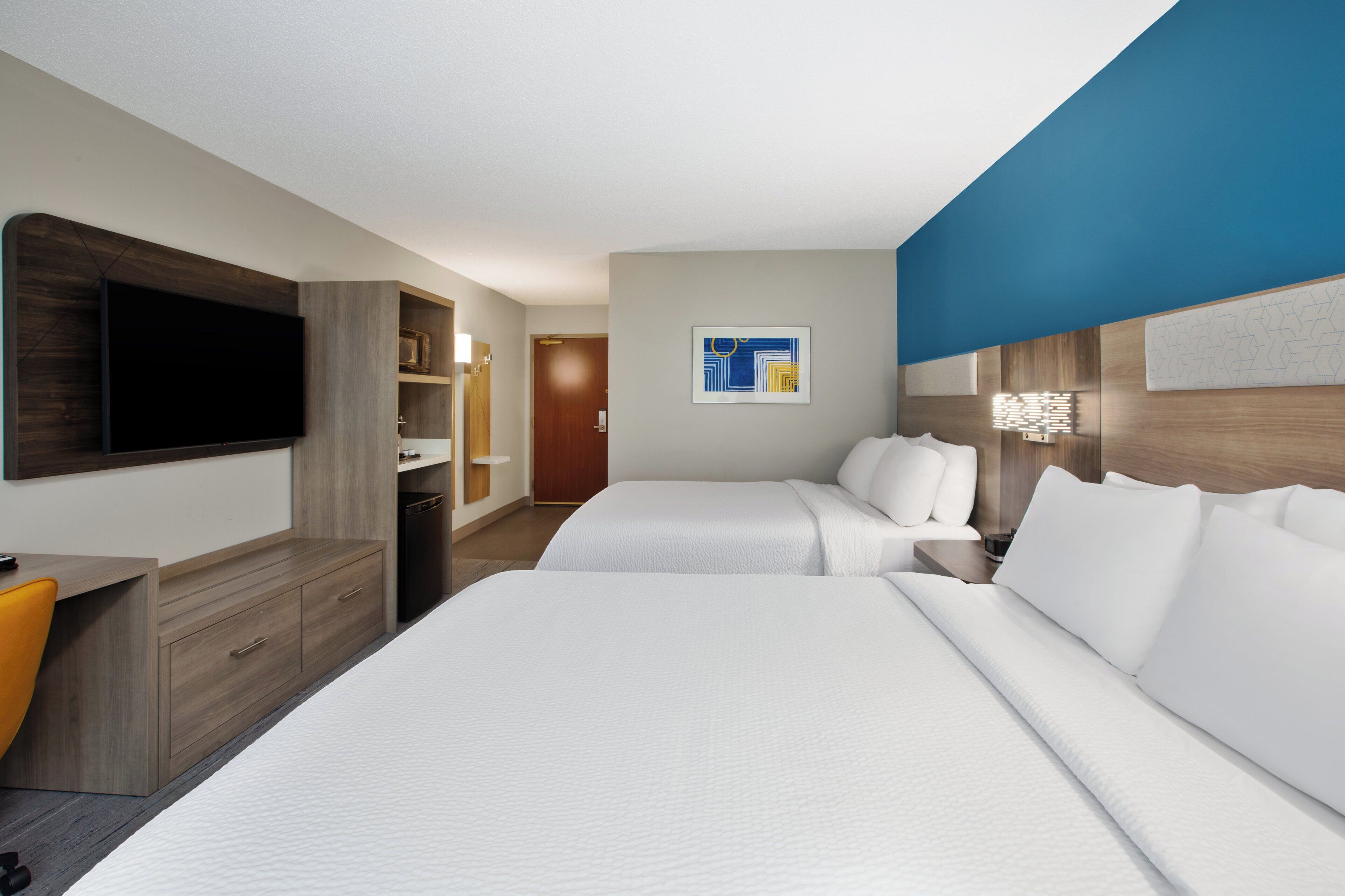 Una habitación de hotel con dos camas, televisor, escritorio y baño.
