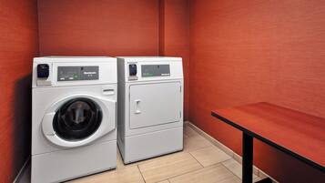 A laundry room with two white front-loading washing machines and a small table.