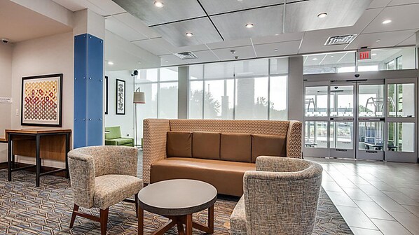 A lobby with a brown sofa, two armchairs, a small table, and a patterned floor. - Holiday Inn Express Hotel & Suites Mount Pleasant by IHG (Mount Pleasant)
