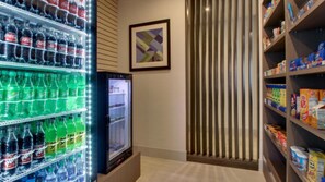 A vending area with various beverages, a refrigerator, and shelves stocked with snacks and cereals. - Holiday Inn Express Hotel & Suites Mount Pleasant by IHG (Mount Pleasant)