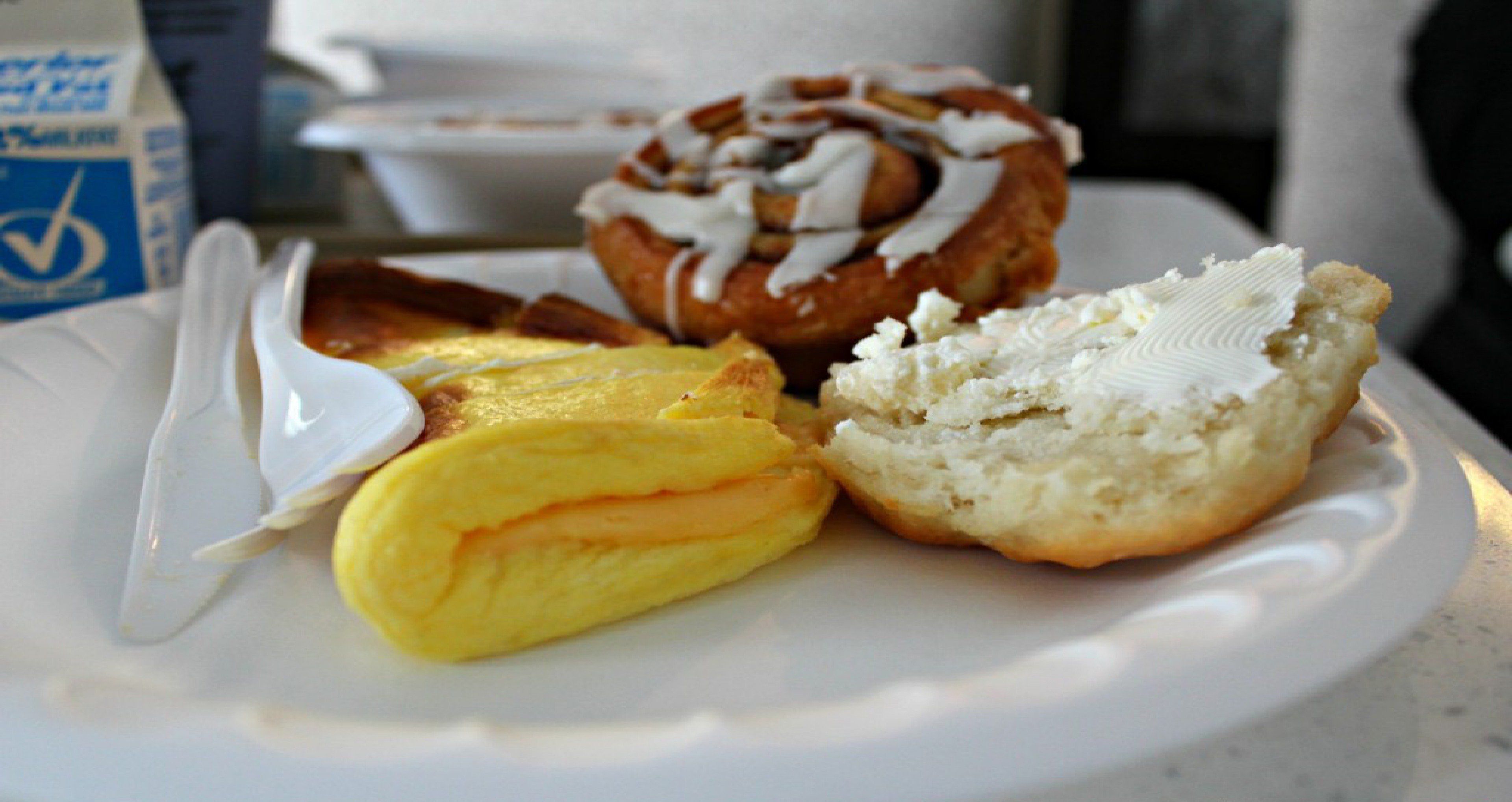 A plate with a pastry, a biscuit, and a folded item, possibly a crepe or pancake, on a white plate.