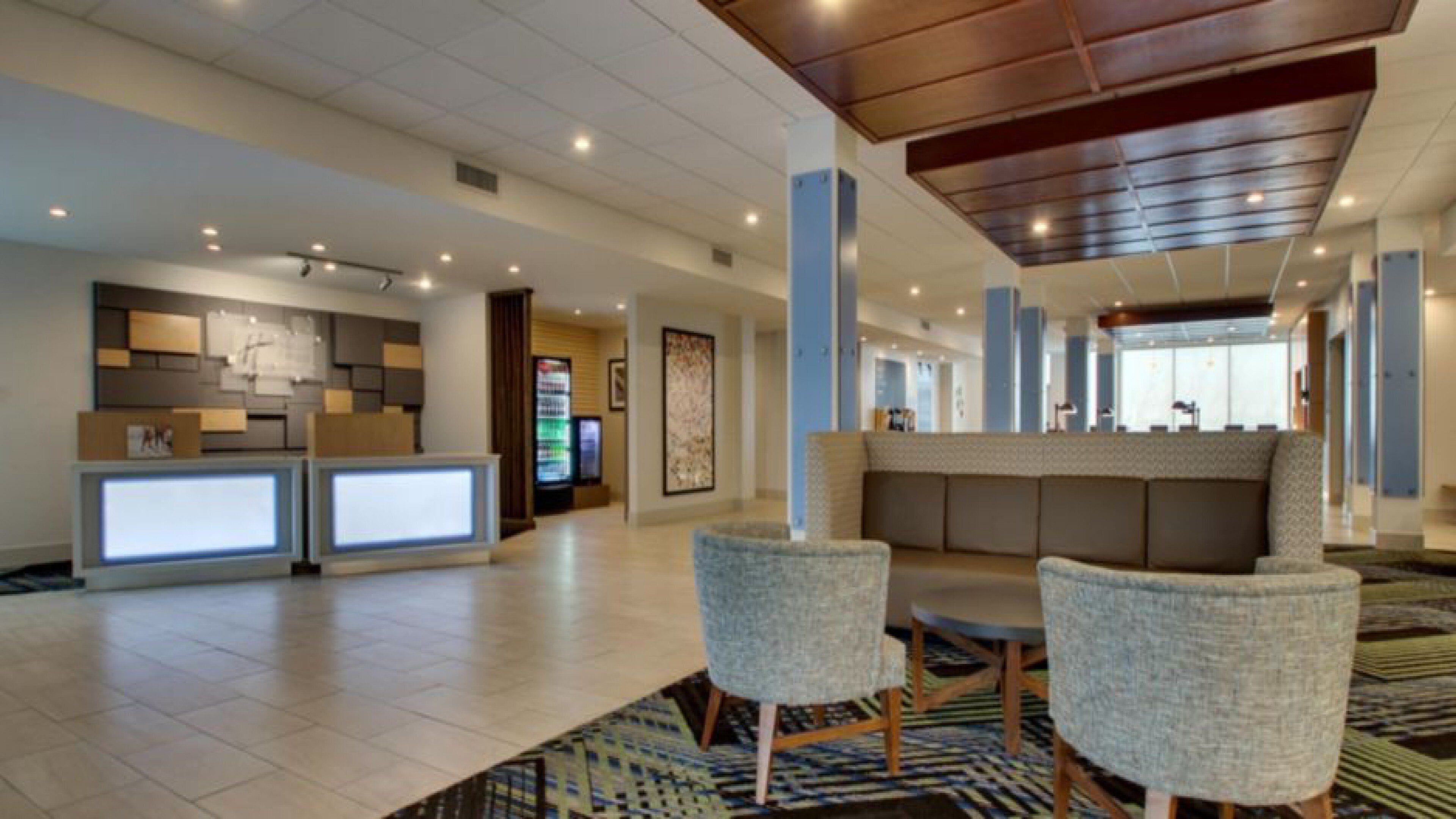 A lobby with a reception desk, seating area, and a large artwork on the wall.