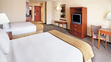 A hotel room with two beds, a desk, a chair, a television, and a minibar.