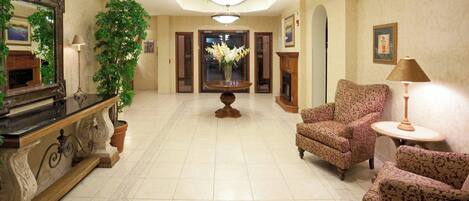 A spacious lobby with a grand chandelier, a fireplace, and a large mirror.