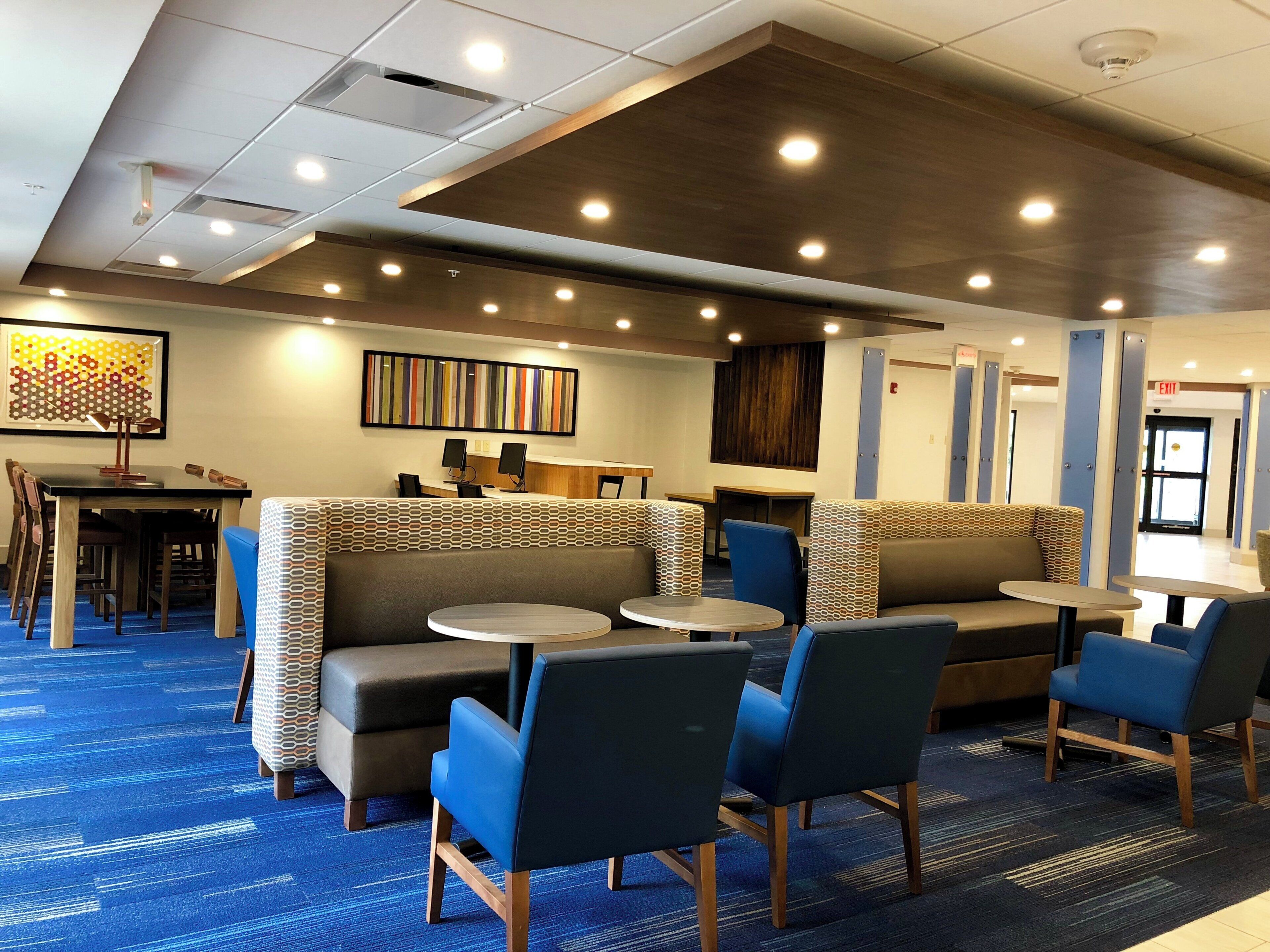 A hotel lobby with seating areas, tables, and a reception desk.