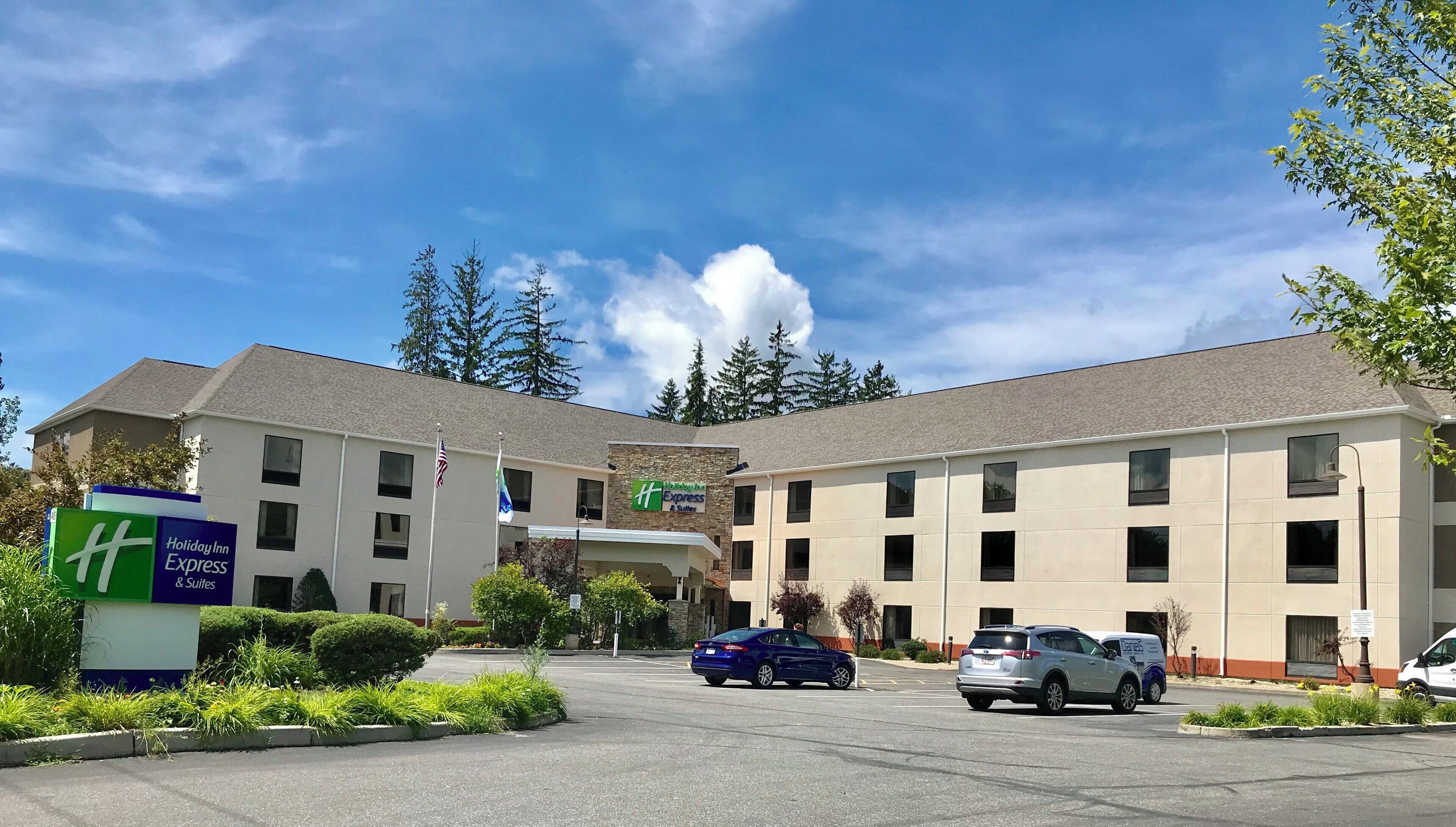 Un hotel Holiday Inn Express & Suites con un parcheggio, un'auto blu e un furgone bianco.