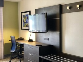 Habitación de hotel con escritorio, silla, televisor y un cuadro en la pared.