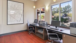 A modern office with a large desk, two monitors, a printer, and a map on the wall.